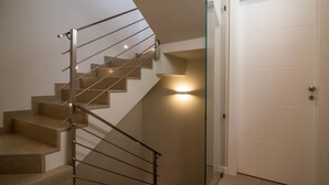 A modern staircase with a glass railing and a lit wall feature.