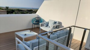 A balcony with a white sofa, a small table, and a blue chair.