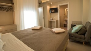 A hotel room with a bed, a seating area, a TV, and a bathroom.