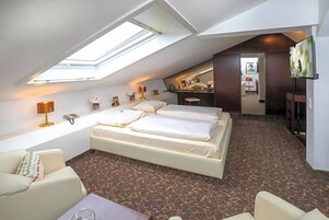 Ein Schlafzimmer mit Dachfenster, einem Bett, einer Couch und einem Fernseher.