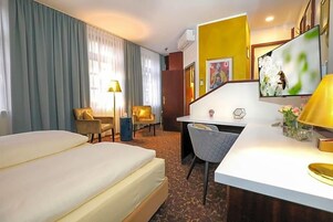 Ein Hotelzimmer mit Bett, Schreibtisch, Stühlen und Fernseher.