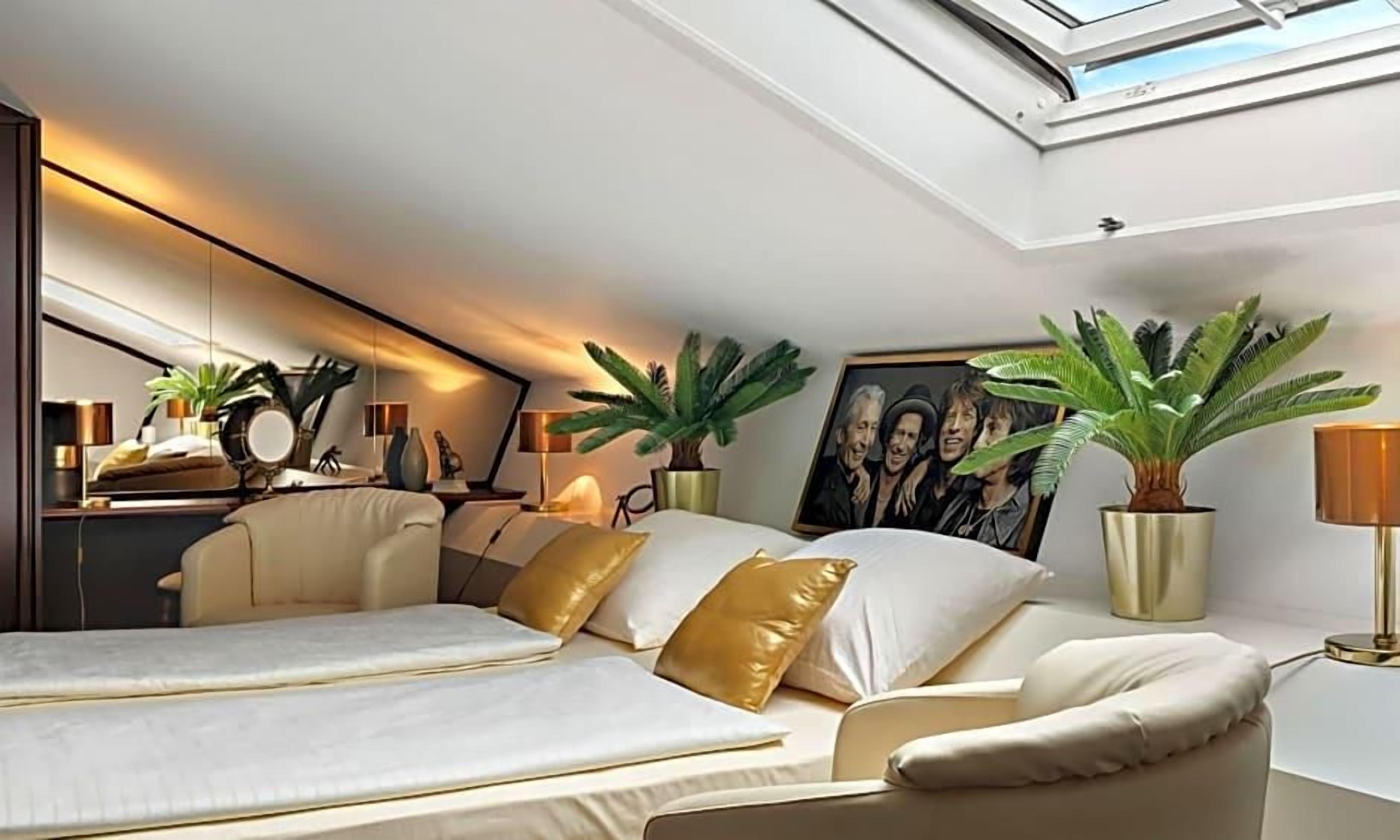 Ein Schlafzimmer mit einem Bett, Nachttischen, Lampen und Topfpflanzen.