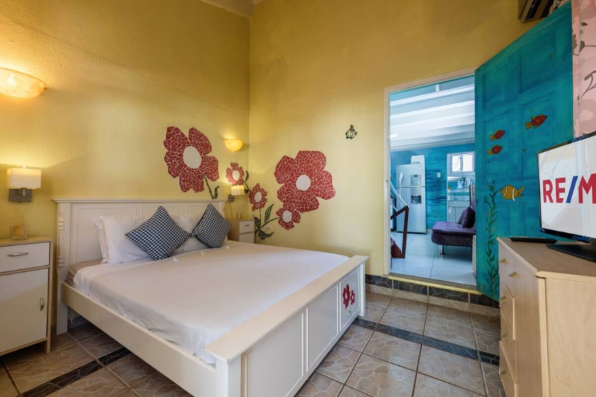 Un dormitorio con cama, mesita de noche, cómoda y televisor.
