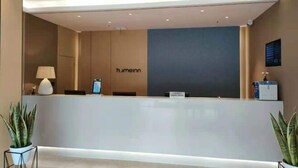 A reception desk with a modern design, a lamp, and a potted plant. - Home Inn (Pizhou Jiefang East Road) (Pizhou)