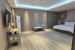 Une chambre d’hôtel moderne équipée d’un lit, d’un coin salon, d’un bureau et d’un miroir.