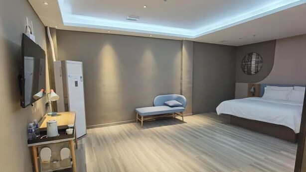 A modern hotel room with a bed, a seating area, a desk with a lamp, and a wall-mounted TV. - Home Inn (Pizhou Jiefang East Road) (Pizhou)
