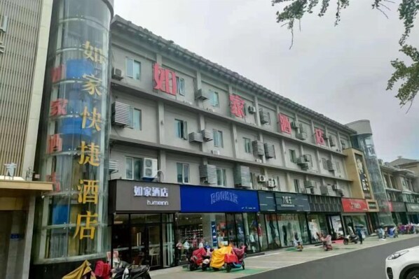 Un immeuble à plusieurs étages, doté de différentes boutiques en rez-de-chaussée, dont une enseigne d’hôtel bien visible.