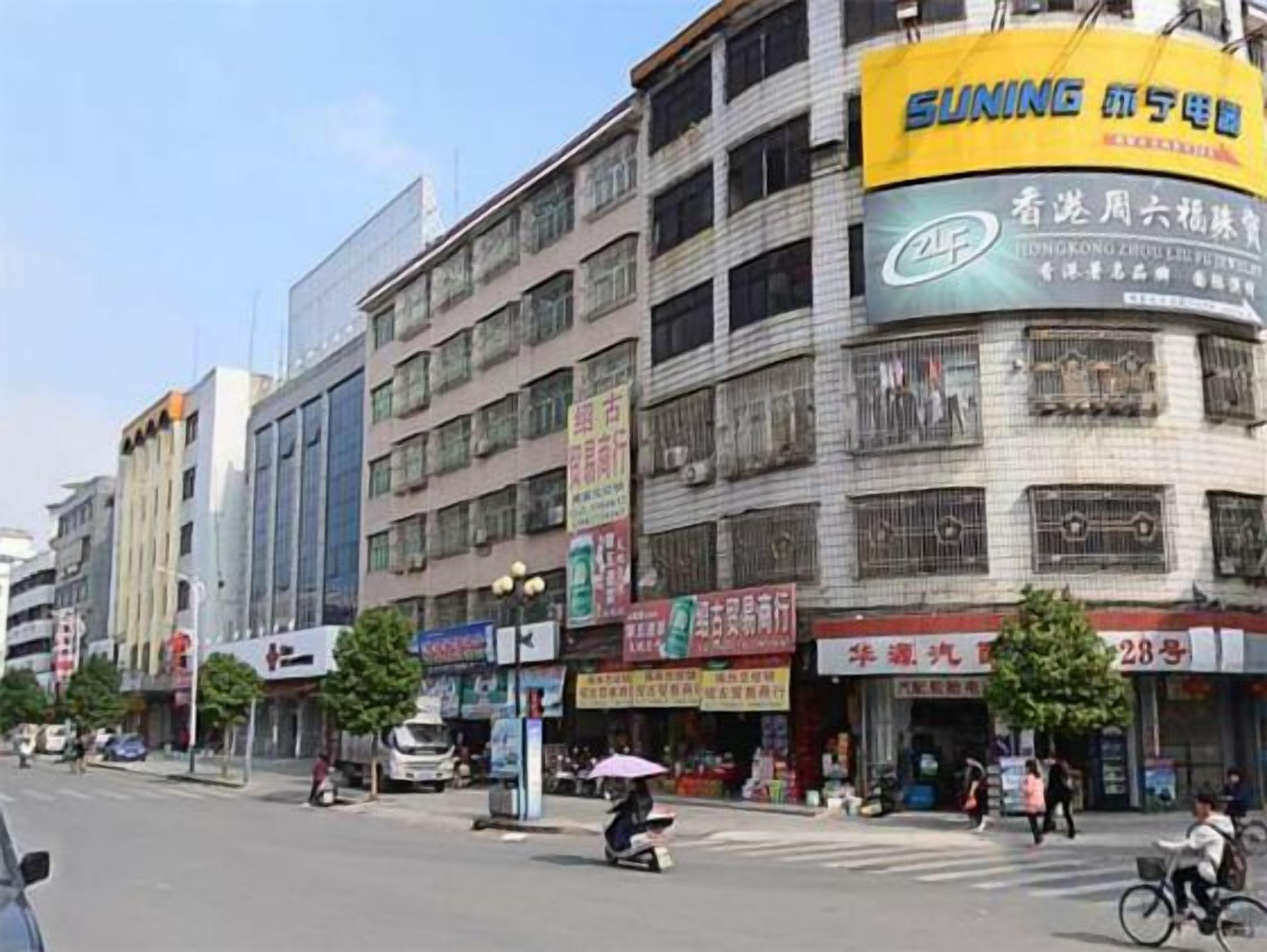 Un immeuble à plusieurs étages dont le rez-de-chaussée abrite divers commerces, notamment une pharmacie et une épicerie.