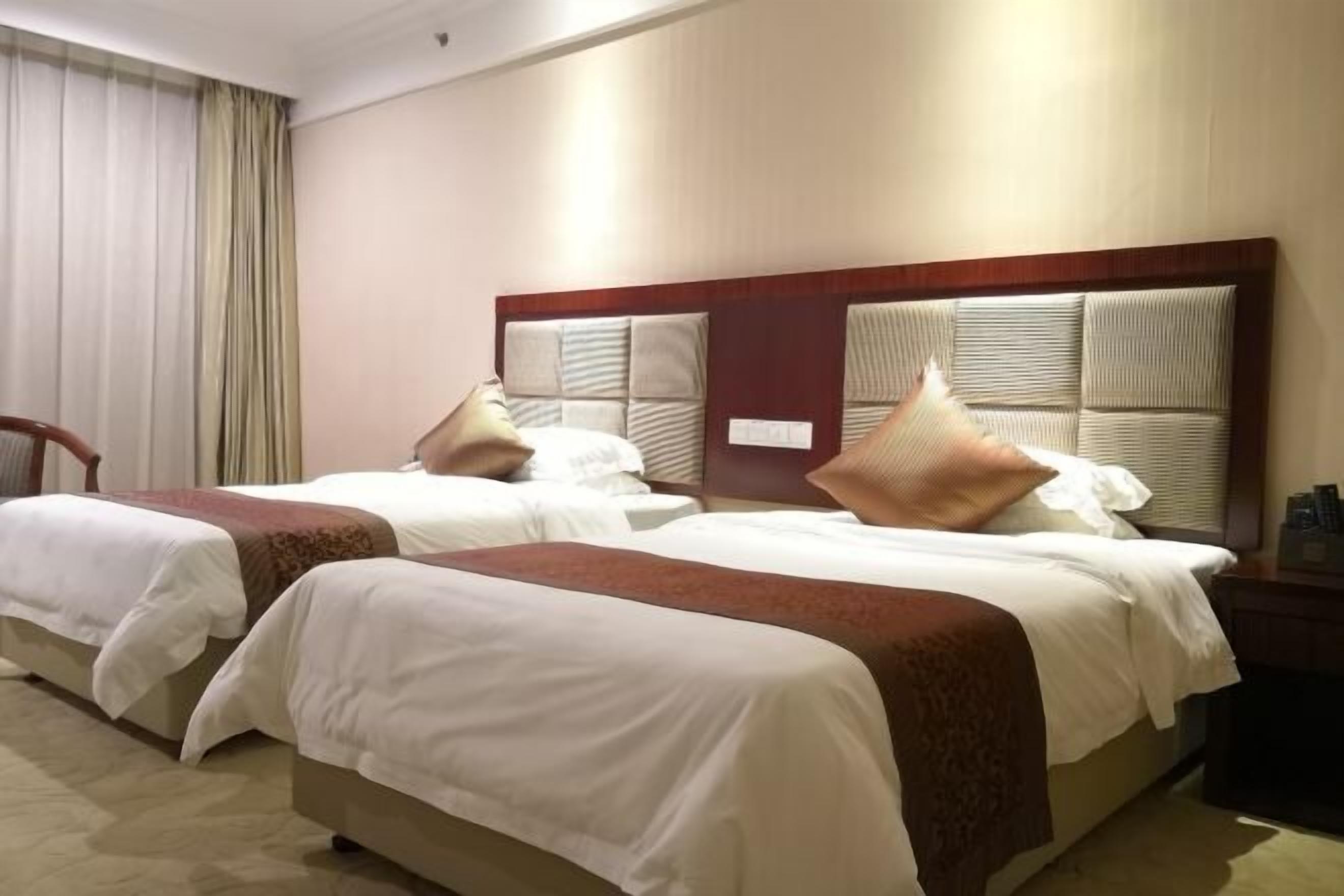 A hotel room with two beds, each with a wooden headboard and white bedding.