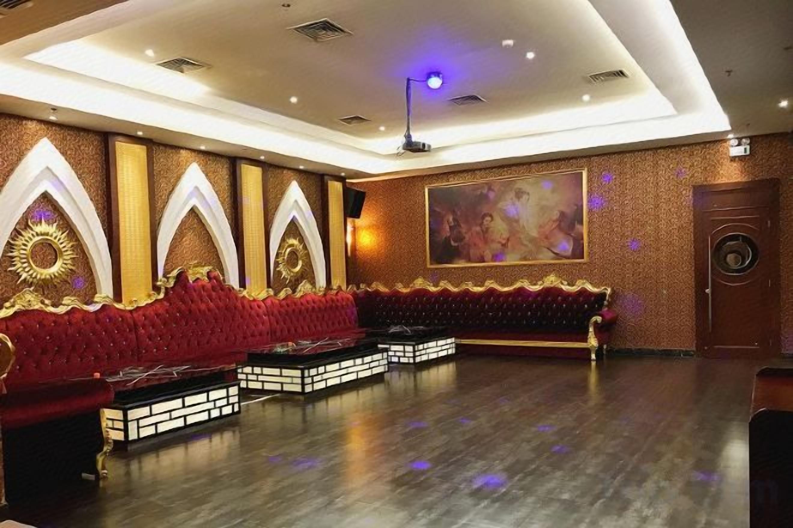 A theater with a red plush seating area, a large painting on the wall, and a stage with a circular backdrop.
