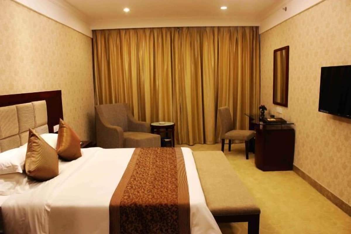 Habitación de hotel con una cama grande, dos sillones, una mesita, televisor y escritorio.