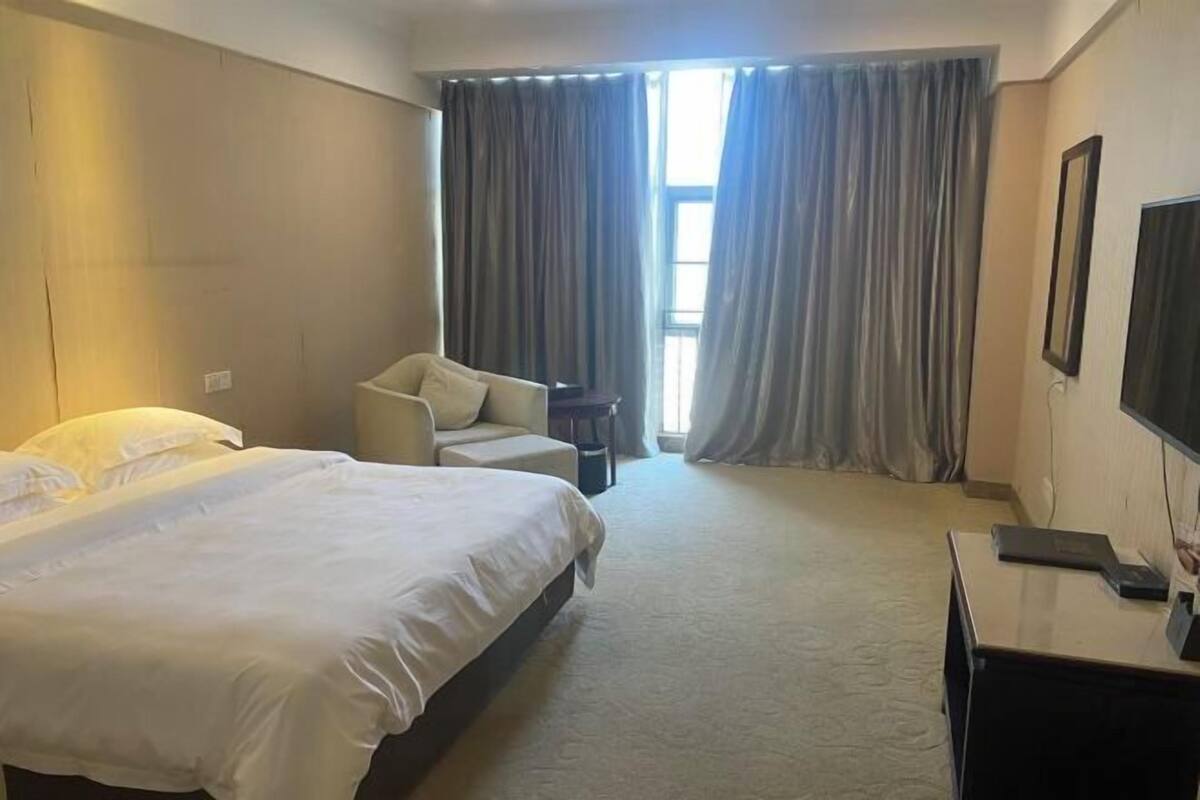 Una habitación de hotel con una cama grande, una silla, un escritorio y un televisor.
