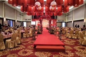 A banquet hall with round tables, a red carpet, and a stage with floral decorations. - Uchoice Hotel (Jiexi)