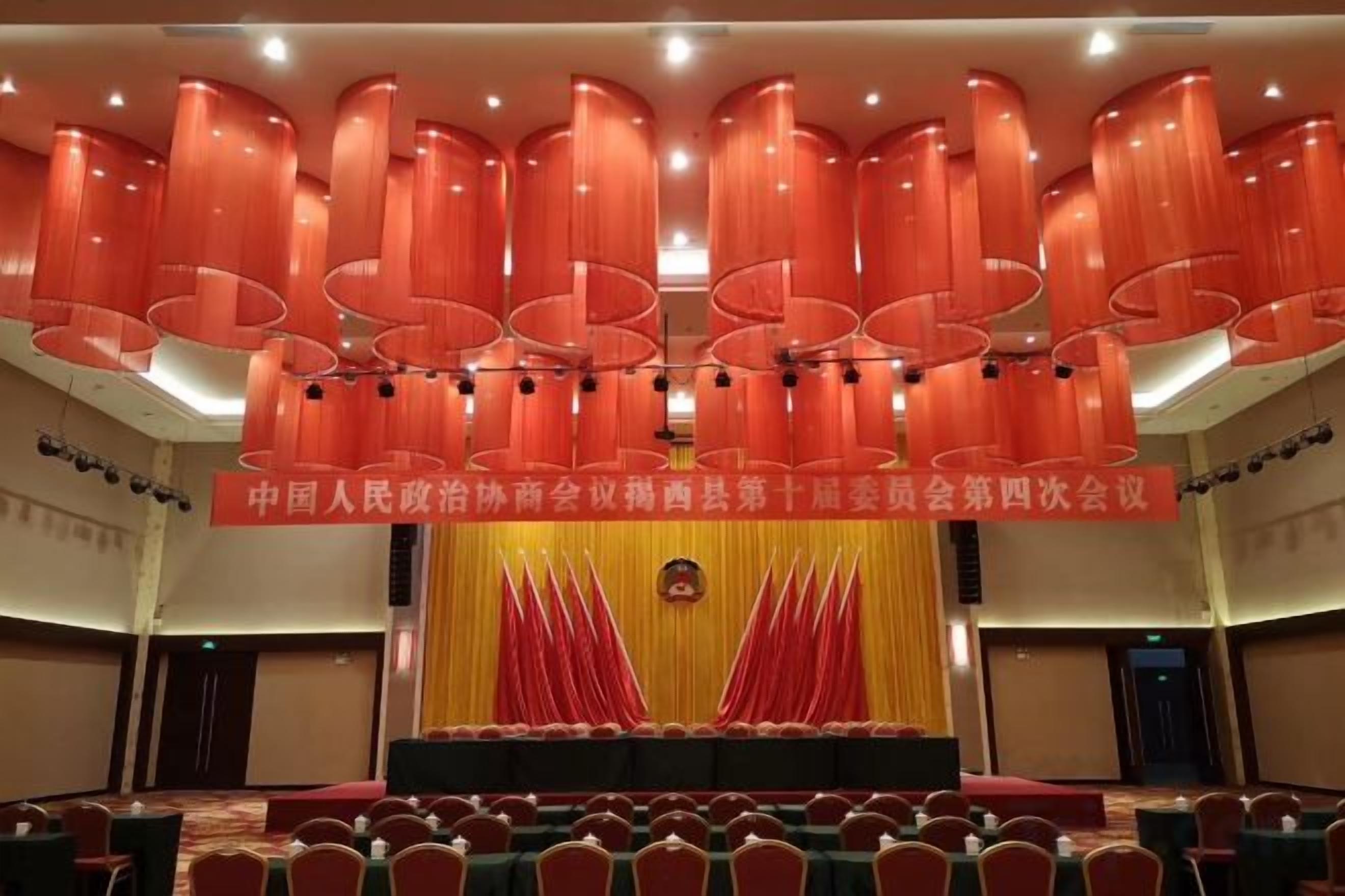 A conference room with a stage, red curtains, and rows of chairs.