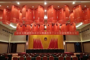 A conference room with a stage, red curtains, and rows of chairs. - Uchoice Hotel (Jiexi)