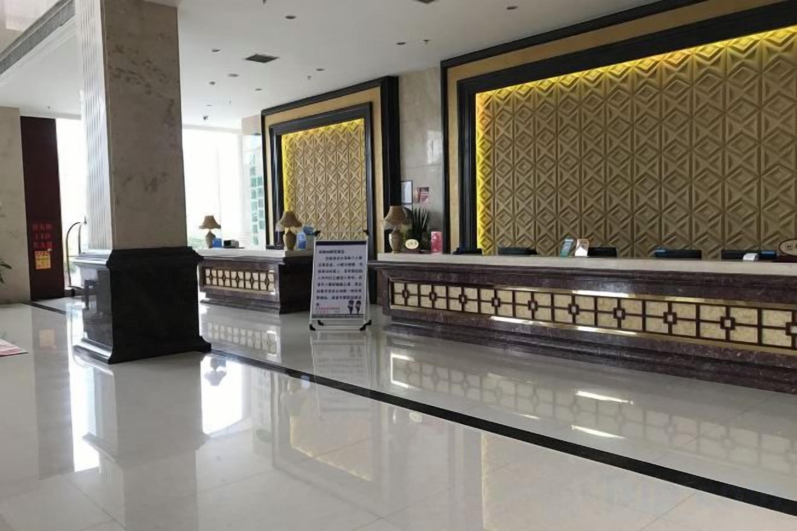 A hotel reception area with a polished floor, a reception desk, and a patterned wall.