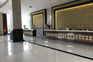 A hotel reception area with a polished floor, a reception desk, and a patterned wall. - Uchoice Hotel (Jiexi)