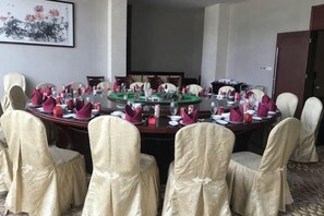 Una sala de conferencias con una mesa redonda, sillas y una pantalla para proyector.