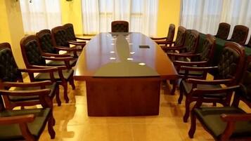 Un salón de conferencias con una gran mesa ovalada rodeada de sillas.