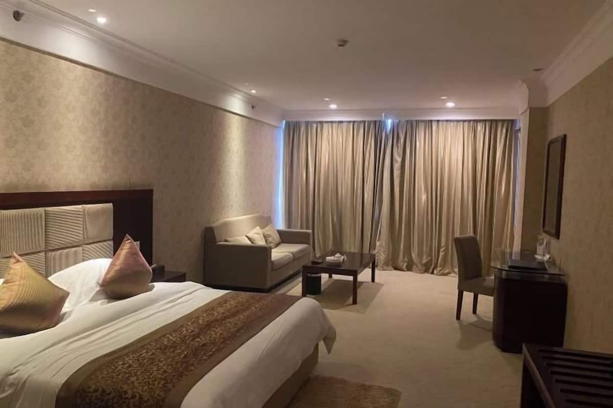 Una habitación de hotel con una cama grande, un sofá, una silla, una mesita y un escritorio.