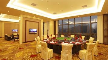A conference room with a round table, chairs, a television, and a large window.
