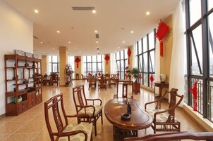 Una habitación amplia con una gran mesa redonda, varias sillas y una estantería.