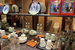 A hotel room's breakfast setup with a buffet table, tea sets, and a mirror reflecting the room. - Uchoice Hotel (Jiexi)