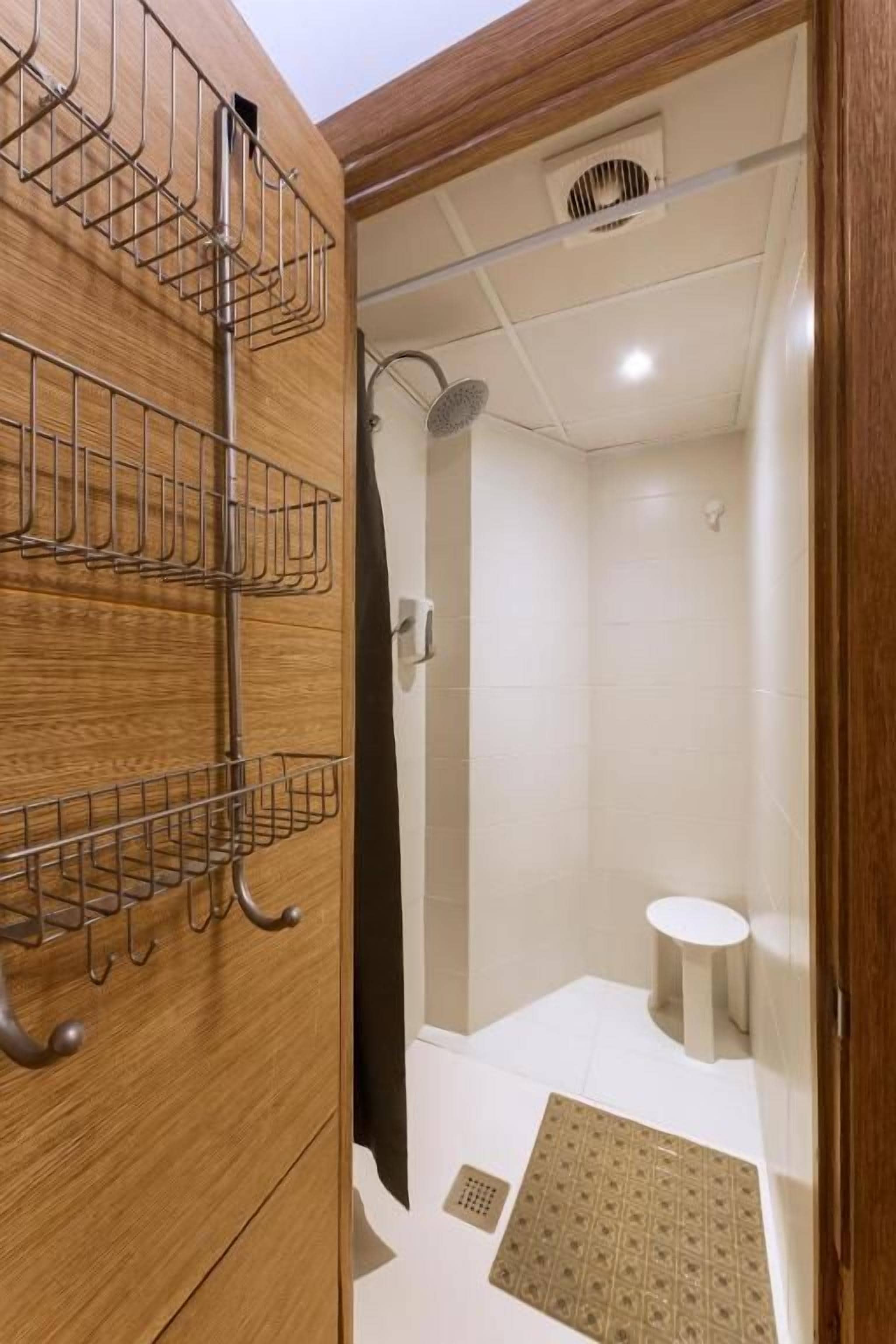 Un baño con tocador de madera, ducha e inodoro.