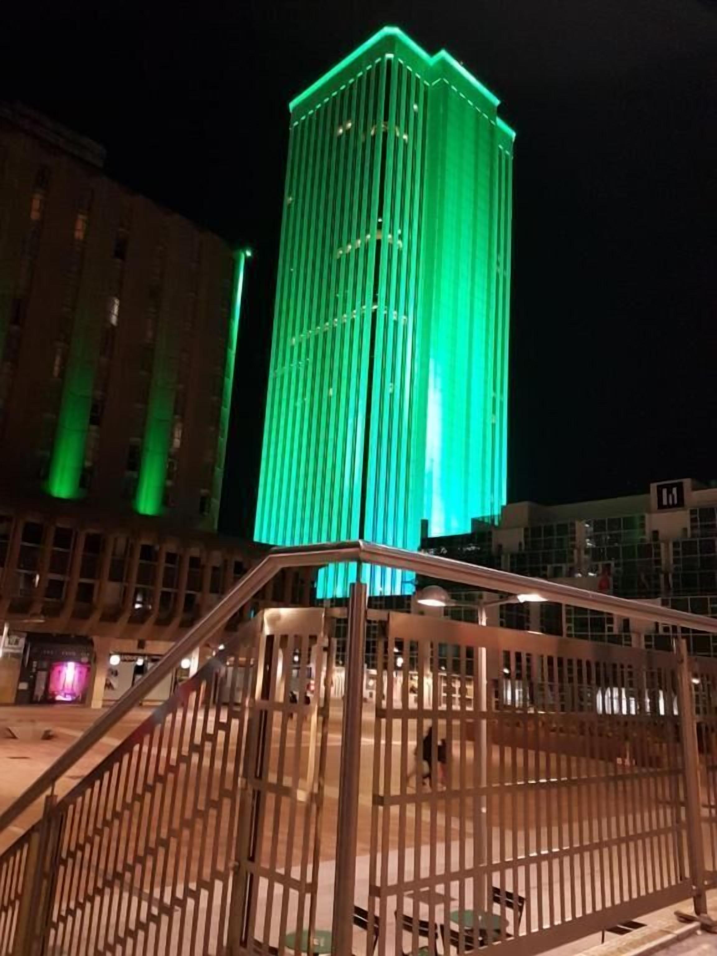 A nighttime view of a building with vertical lines and a green light.