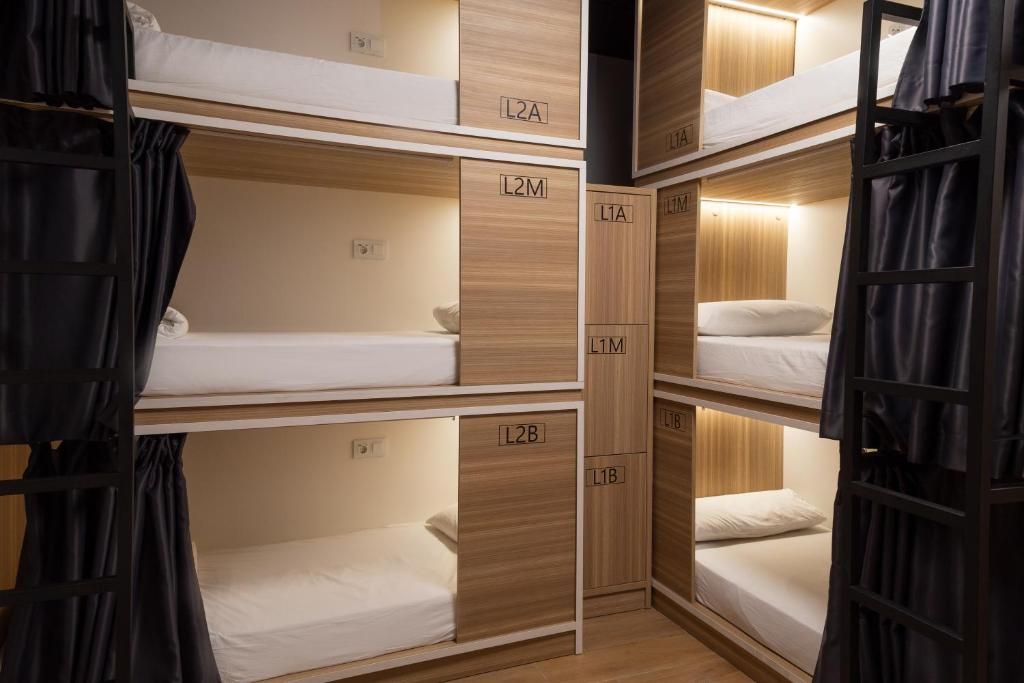Une chambre avec des lits superposés à plusieurs niveaux, chaque lit étant doté d’un compartiment individuel identifié par les lettres L1A à L2B.