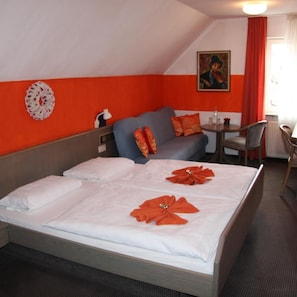 A hotel room with a bed, a sofa, a small table, and a chair.