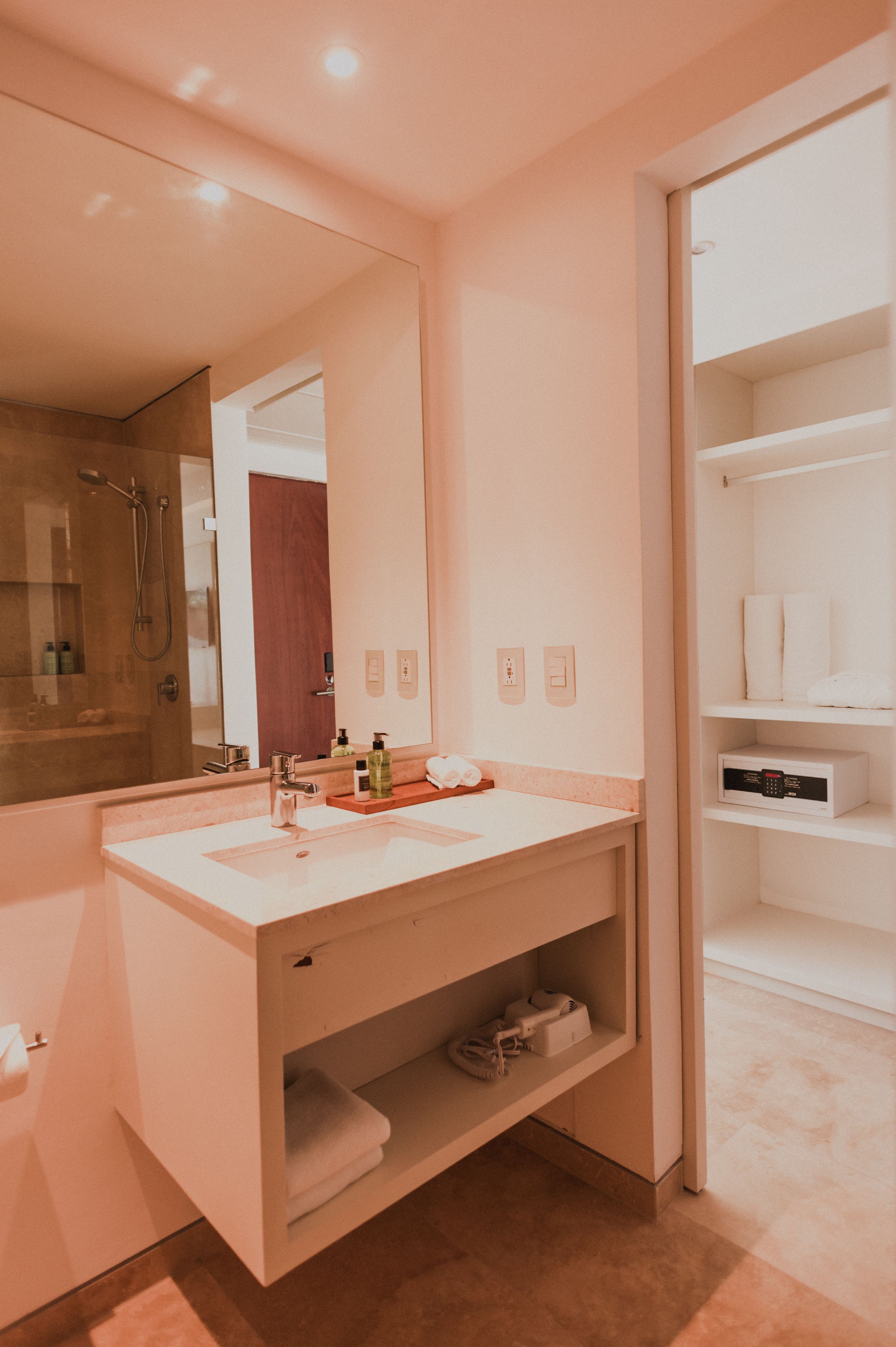 Un baño moderno con un espejo grande, un tocador blanco y zona de ducha.