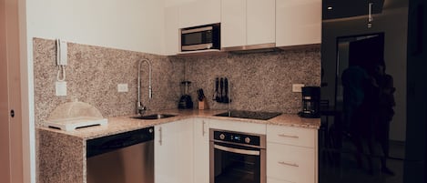 Una cocina moderna con encimeras de granito, electrodomésticos de acero inoxidable y muebles de cocina blancos.