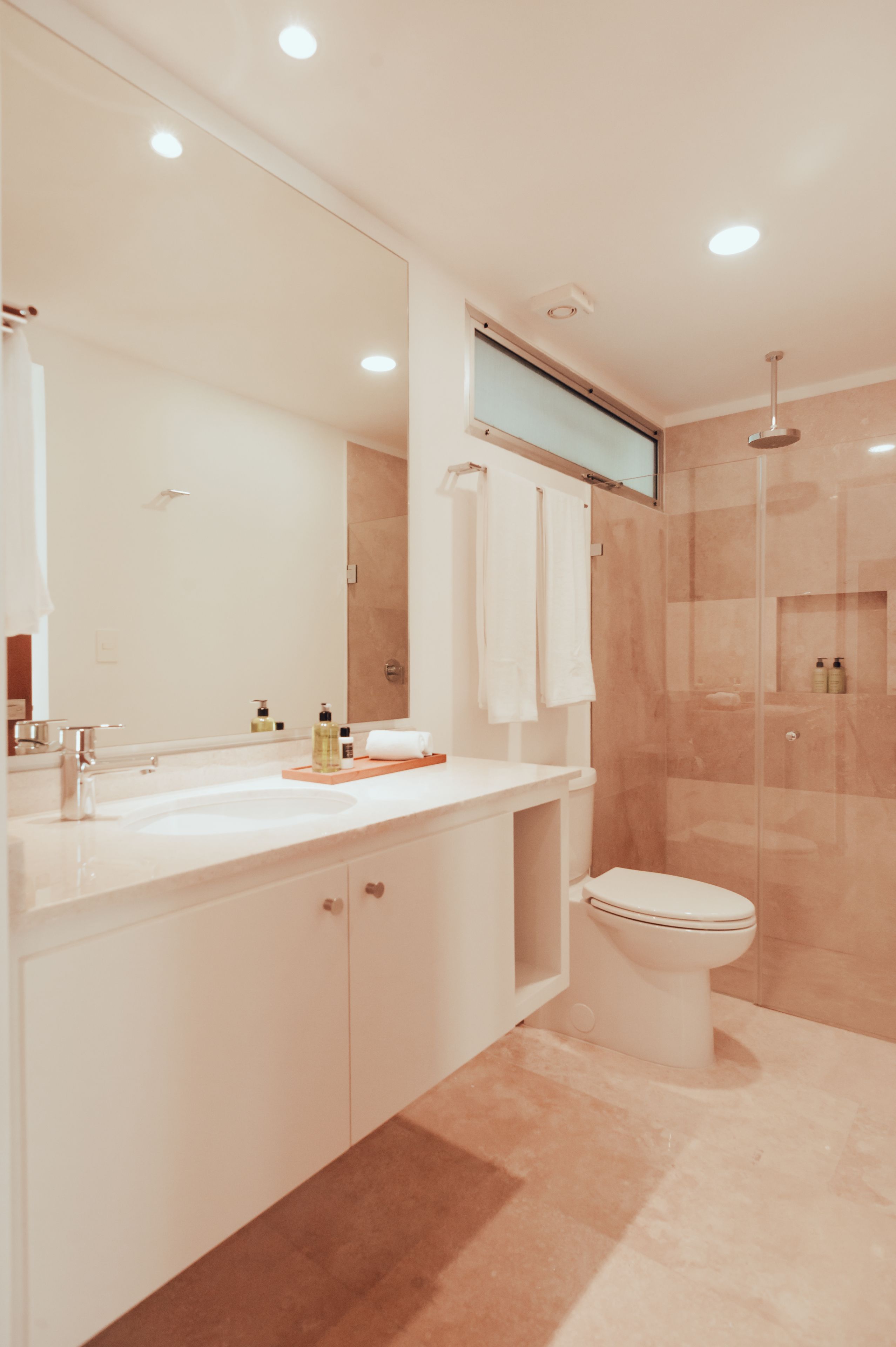 Een moderne badkamer met een grote spiegel, een wastafel, een toilet en een douchehoek.