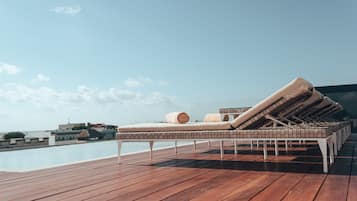 Eine Holzterrasse mit Liegebereich am Pool, ausgestattet mit Liegestühlen und Handtüchern.