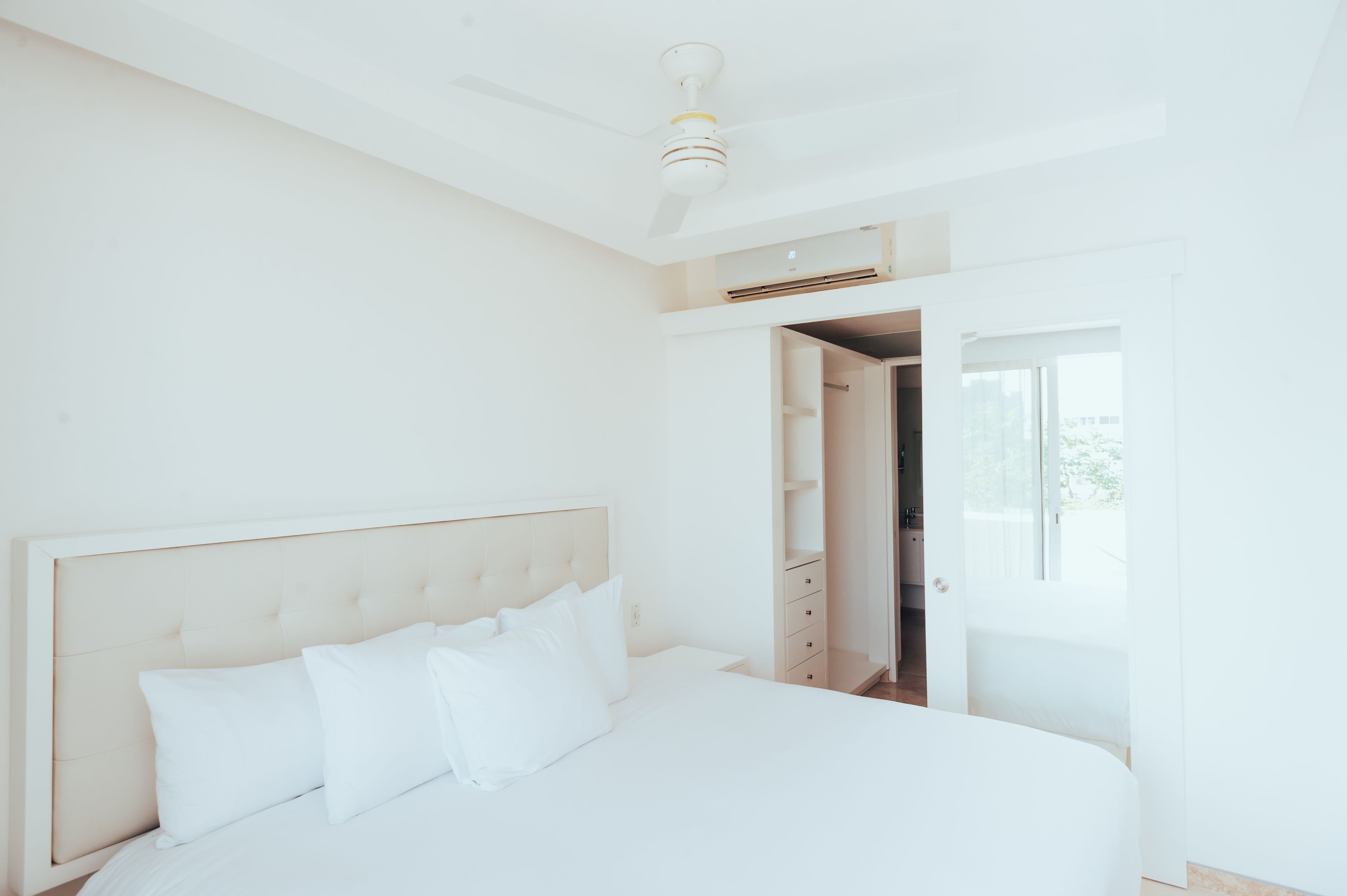 A bedroom with a large bed, a ceiling fan, and a wardrobe.