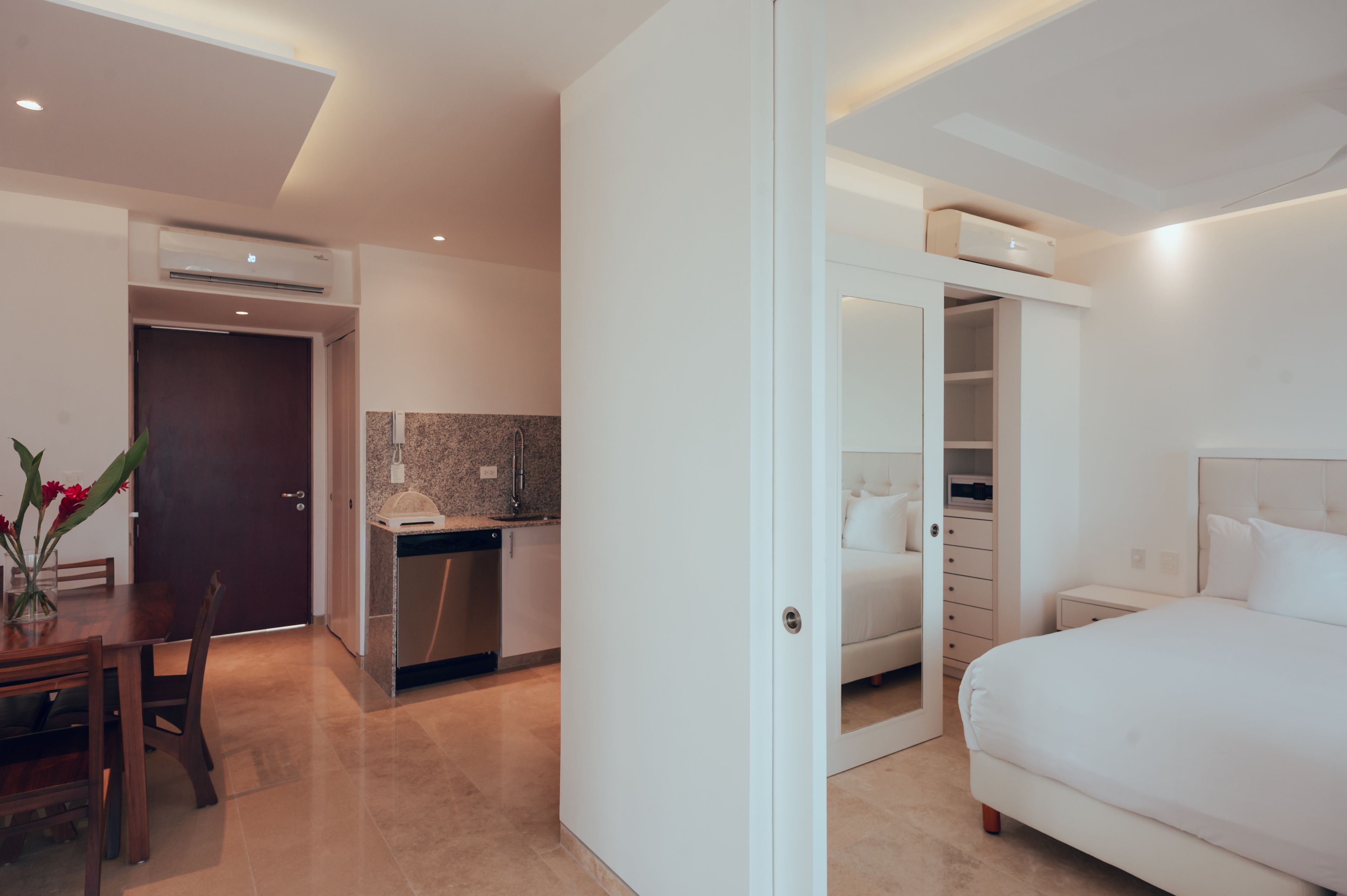 Ein modernes Hotelzimmer mit einem großen Bett, einem separaten Badezimmer, einer Küchenzeile und einem Essbereich.