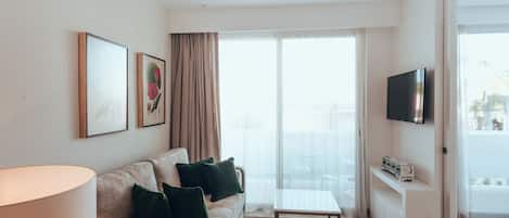Un salon moderne comprenant un canapé, une table basse, un téléviseur à écran plat et un ventilateur de plafond.