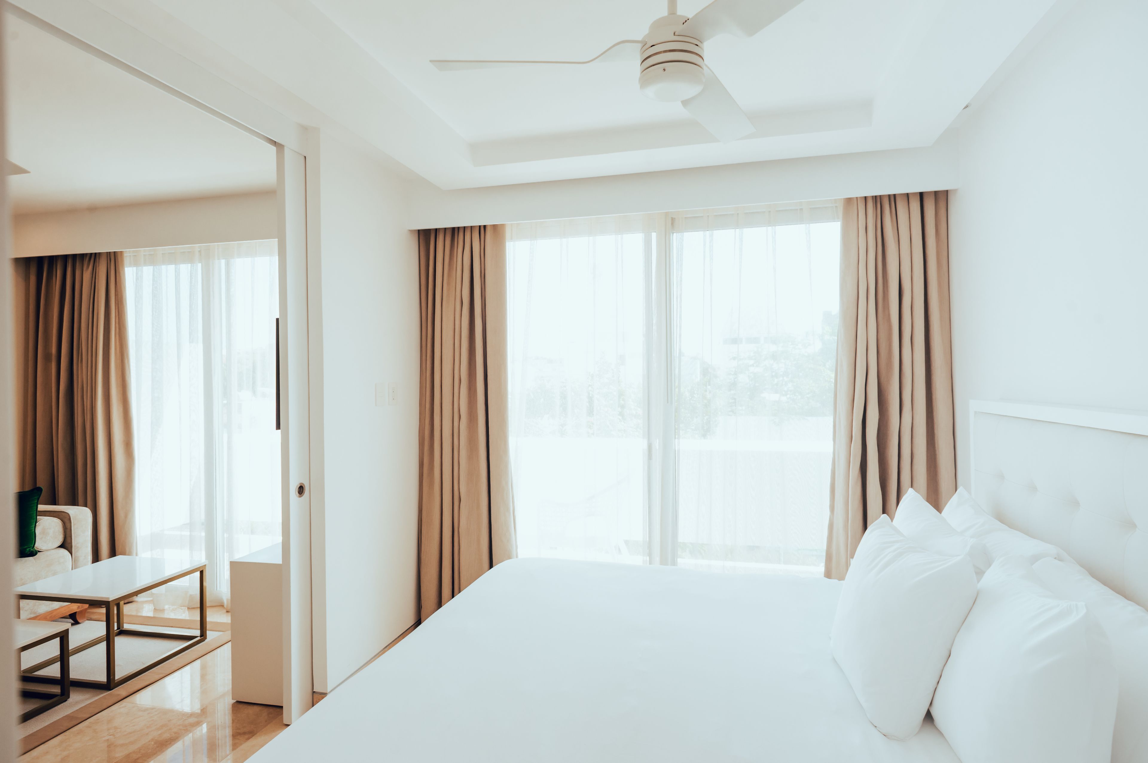Habitación de hotel con una cama grande, un escritorio y vistas a la ciudad a través de amplios ventanales.