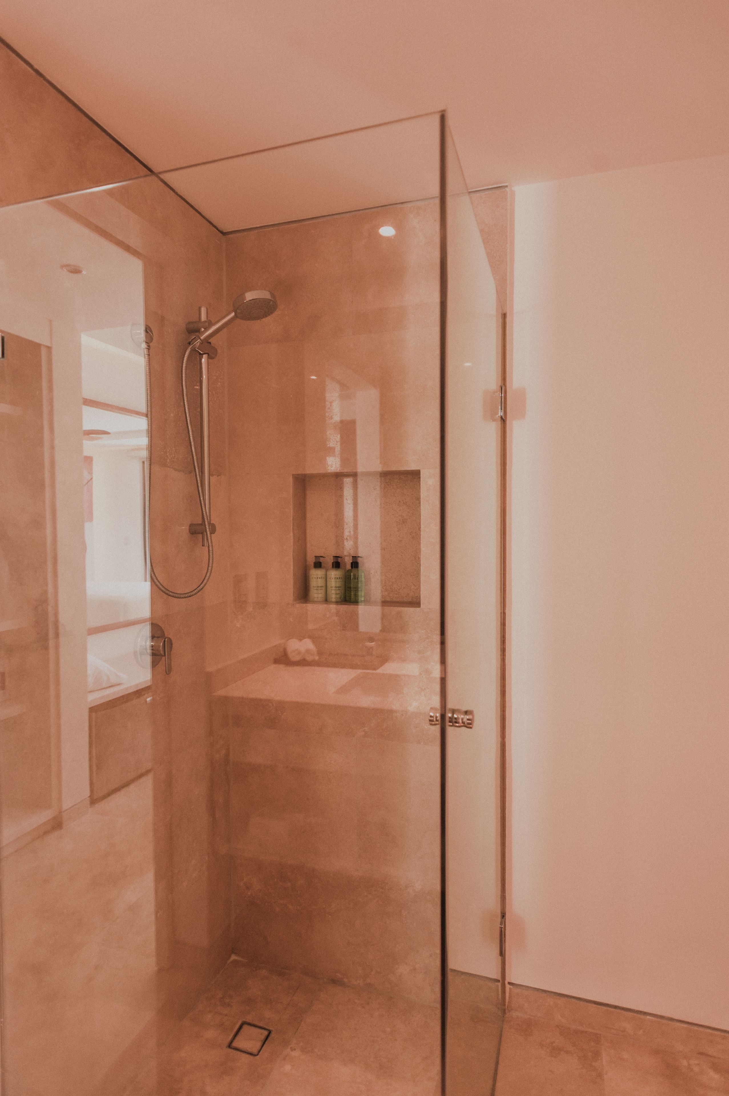 Een moderne badkamer met een douchecabine van glas, een wastafel met spiegel en een plank met toiletartikelen.
