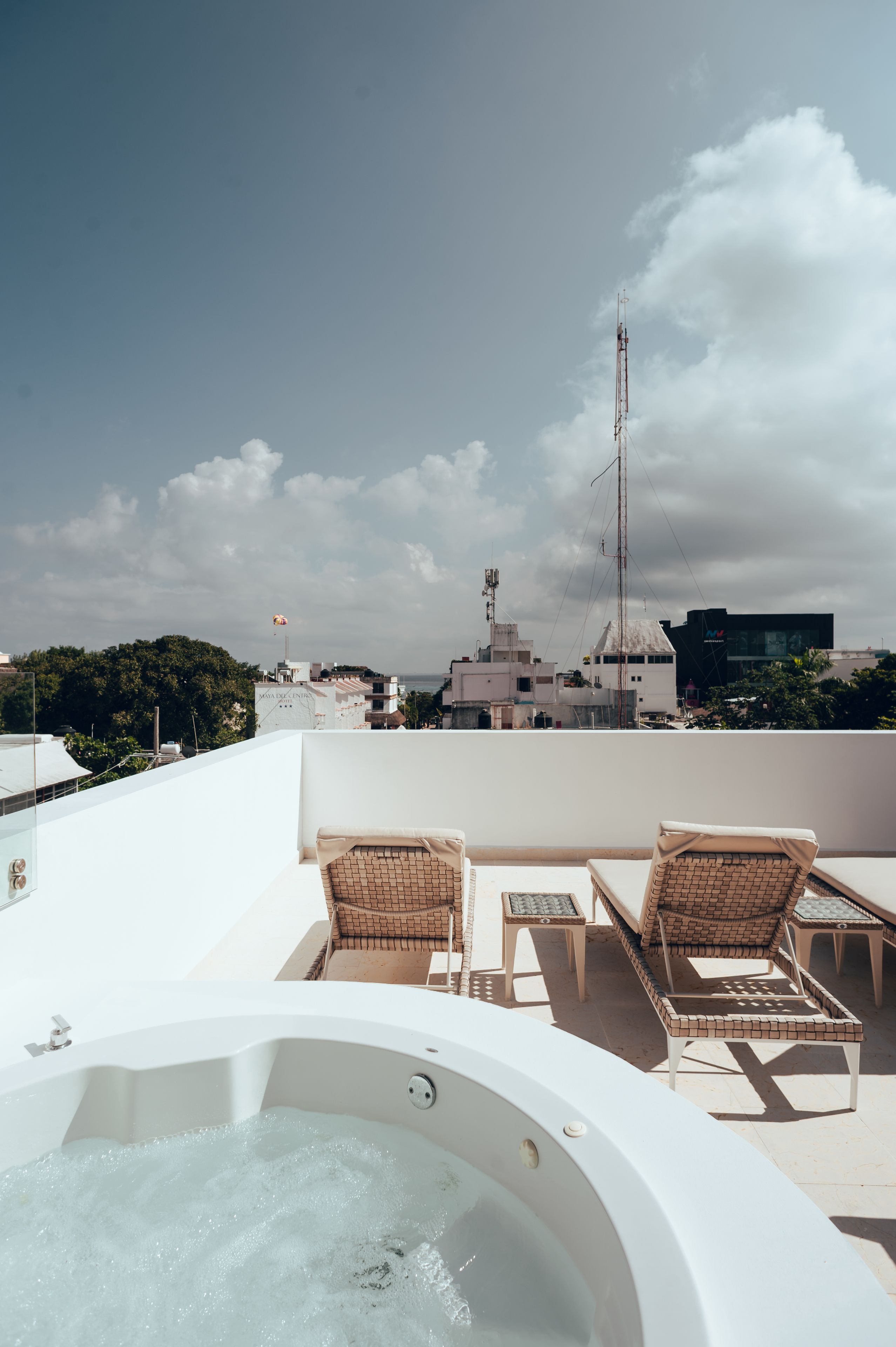 A rooftop terrace with a hot tub, lounge chairs, and a view of the cityscape.