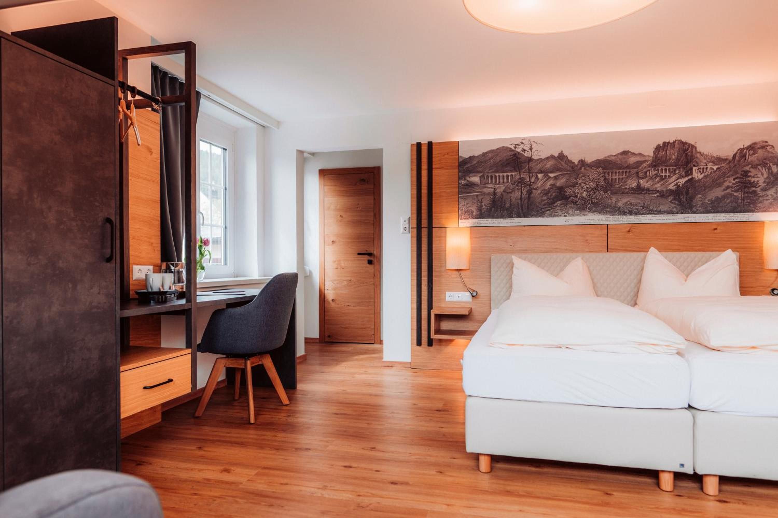Ein modernes Schlafzimmer mit Bett, Schreibtisch, Stuhl und einem großen Gemälde an der Wand.
