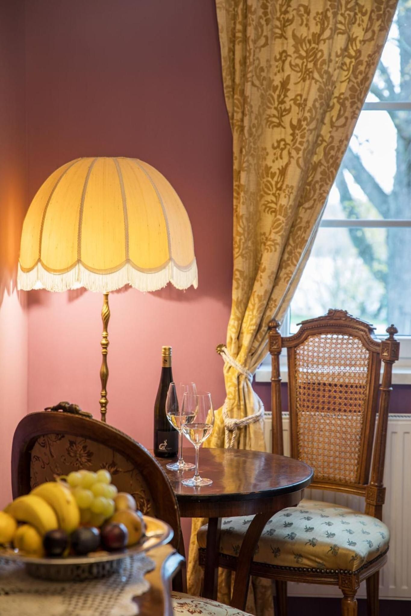 A dining area with a table set for two, a bottle of wine, and a fruit bowl.