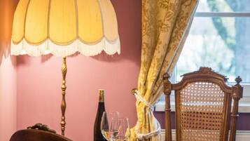 A dining area with a table set for two, a bottle of wine, and a fruit bowl.