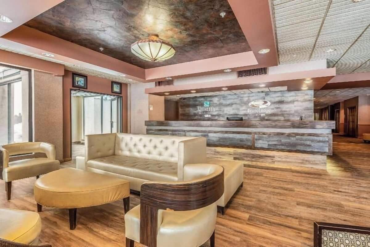 A lobby with a reception desk, a seating area with sofas and chairs, and a wooden floor.