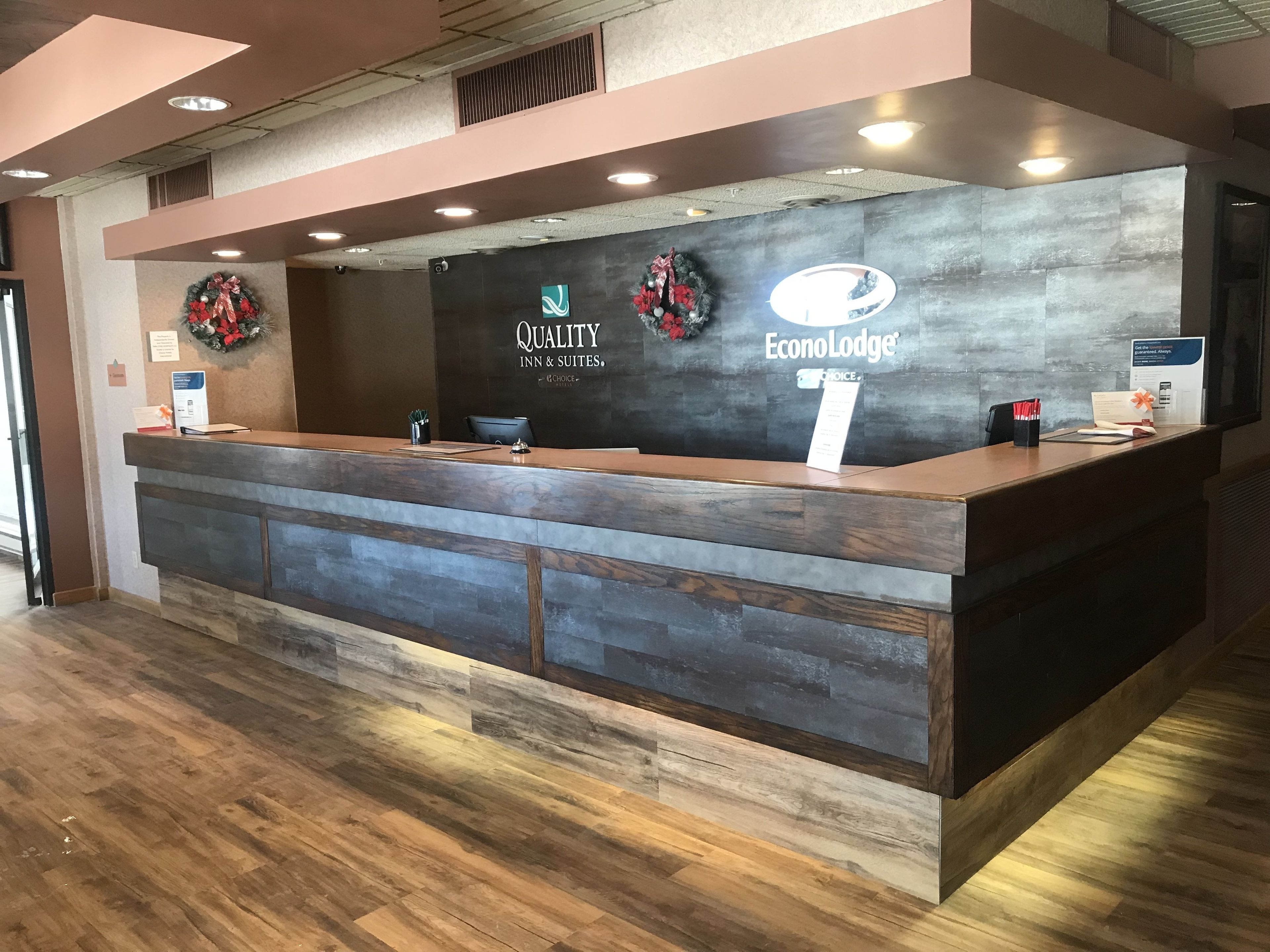A reception desk with a dark wood finish, a sign for 'Quality Inn & Suites', and a logo for 'EconoLodge'.