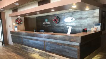 A reception desk with a dark wood finish, a sign for 'Quality Inn & Suites', and a logo for 'EconoLodge'.