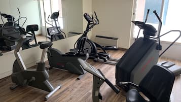 A gym with various exercise machines, including an elliptical and a stationary bike.
