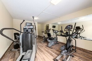 A gym with various exercise machines, a mirror, and a wooden floor. - Quality Inn & Suites Brainerd (Brainerd)