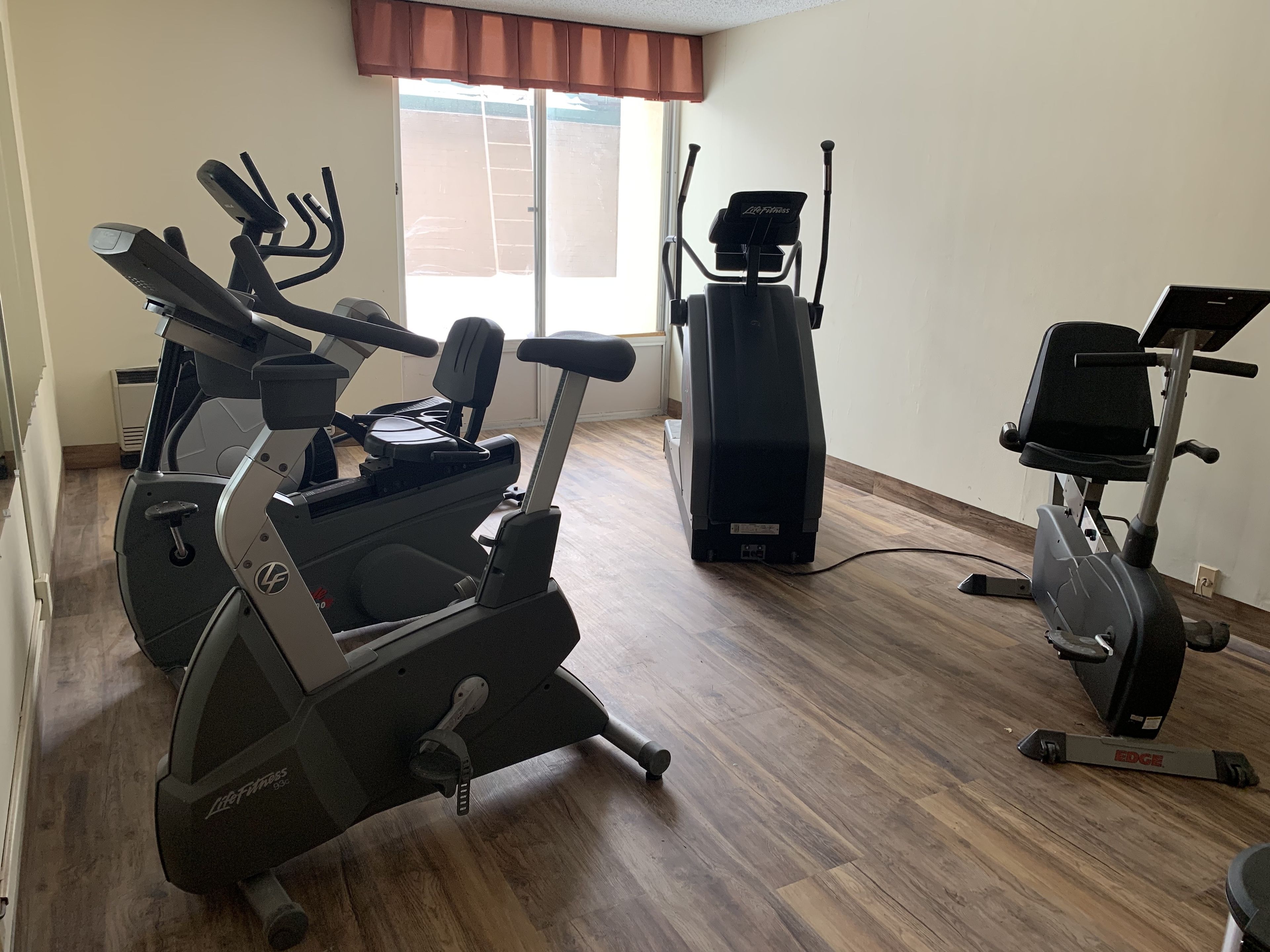 Gimnasio en casa con equipo de cardio, incluyendo una elíptica y una bicicleta estática.